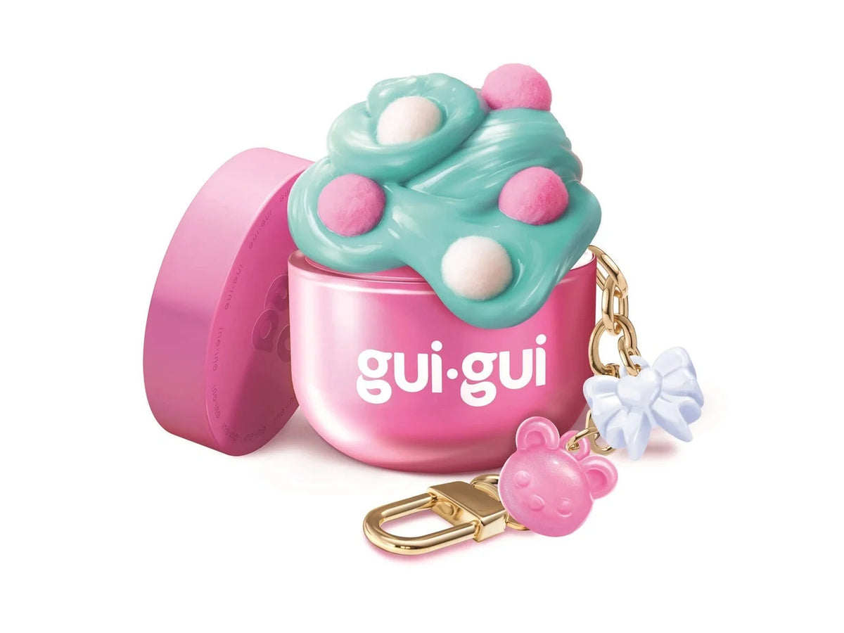 Gui Gui Mini Single open pink jar overflowing with teal butter slime decorated with pink pompoms, with gold chain keyring charm featuring a pink bear and blue bow pendant